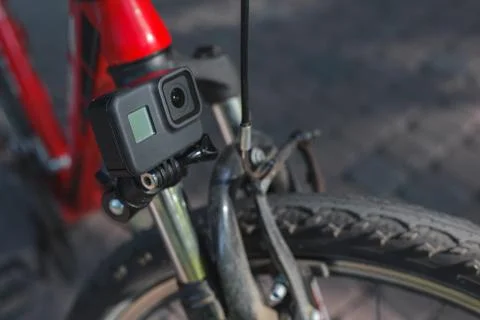 Action camera with a screen on, mounted next to a mountain bike wheel Stock Photos