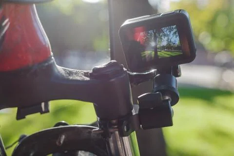 Action camera with a screen on, mounted next to a mountain bike wheel Stock Photos
