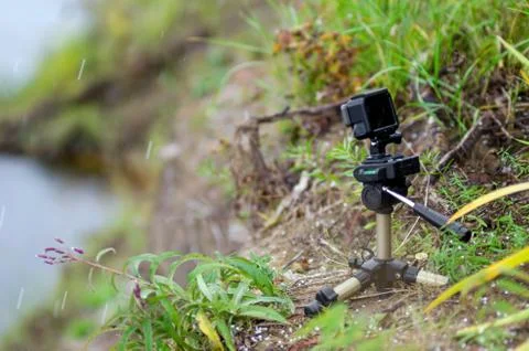 Action camera on a small tripod stands in the grass of the river. Stock-Fotos