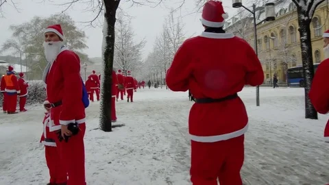 Action camera smoothly following crowd of Santa Clauses running from behind Stock Footage 70638721
