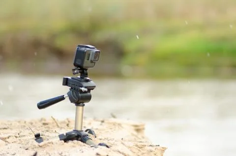 Action camera stands on a small tripod, recording video, on the sandy Bank. Stock Photos