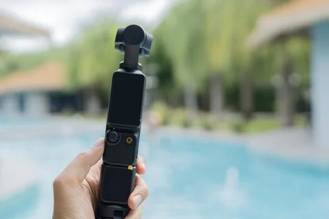 Action camera with three-axis suspension on woman hand over swimming pool Stock Photos