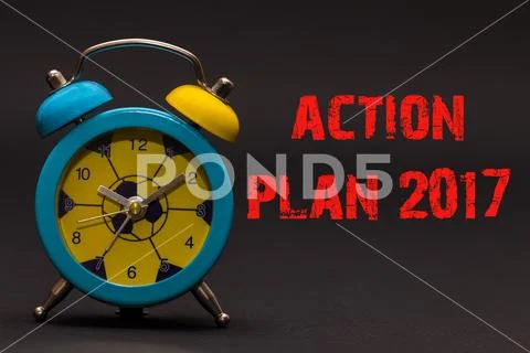 Action Plan 2017 written with alarm clock on black paper background ...