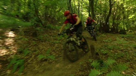 Action shot of two pro downhill cyclists passing by in the woods Stock Footage 55916118