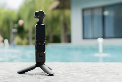 Action small camera and tripod setting on floor nearby a swimming pool back.. Stock Photos
