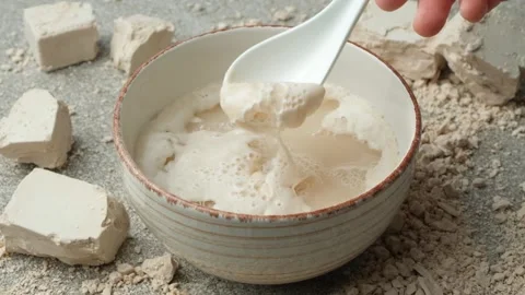 Activation of wet fresh yeast in warm water with sugar, foam and bubbles, slow Stock Footage 309766609