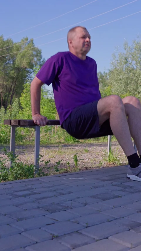 Active 62 year old man doing exercises on the sports ground. Triceps push-ups. Stock Footage 310439572