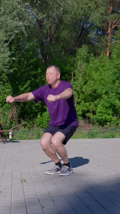Active 62 year old man doing exercises on the sports ground. Squats. Stock Footage 310770138