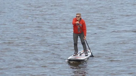 Active aged man swims on SUP board on a river Видео 81113395