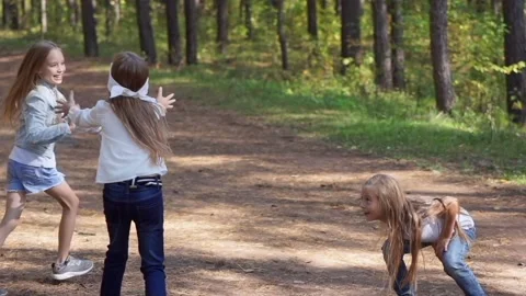 An active and cheerful group of children play hide and seek in a summer park Stock Footage 154701656