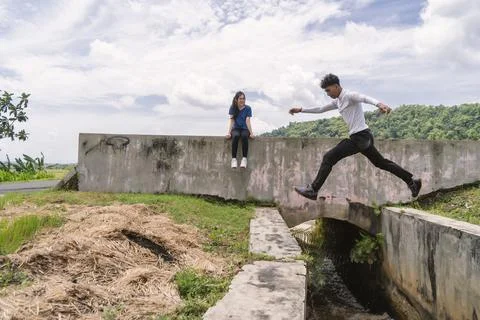 Active asian couple resting while the young man jump Stock Photos