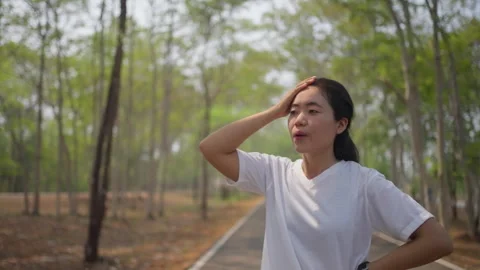 An active Asian female runner taking a break to catch her breath Stock Footage 274462307
