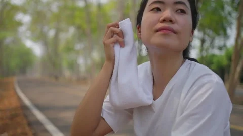 An active Asian female runner taking a break to catch her breath Stock Footage 274468803