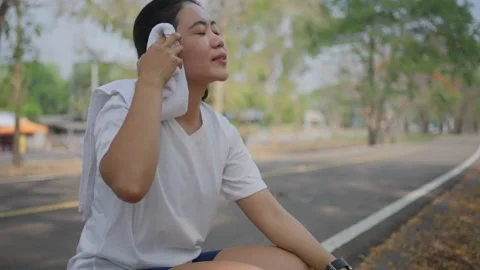 An active Asian female runner taking a break to catch her breath Stock Footage 274469167