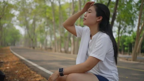 An active Asian female runner taking a break to catch her breath Stock Footage 274469548