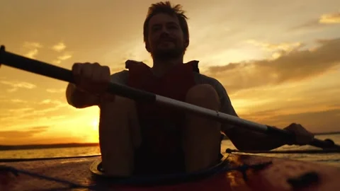 An active, athletic young man is sailing on a boat against the sunset. Stock Footage 140256736