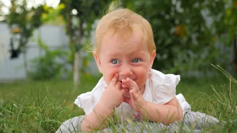 Active baby background. Toddler teething problems. Baby girl lying on green Stock Footage 100791743