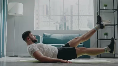 Active bearded athlete guy in t-shirt and shorts trains abs Stock Footage 152734029