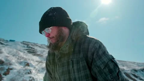 Active bearded man in glasses puts white snow block closeup Stock Footage 132475180