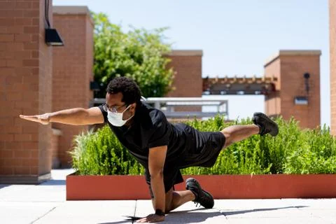 Active black man does Yoga poses in protective mask during covid-19 quarantine Stock Photos