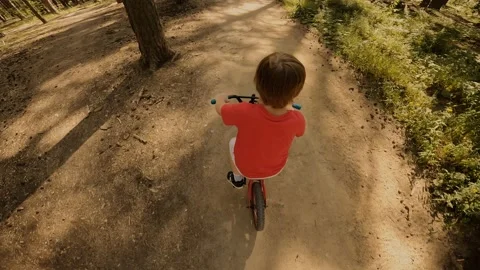 Active boy child fast riding bike on forest off road surrounded by sunny natural Stock Footage 219434304