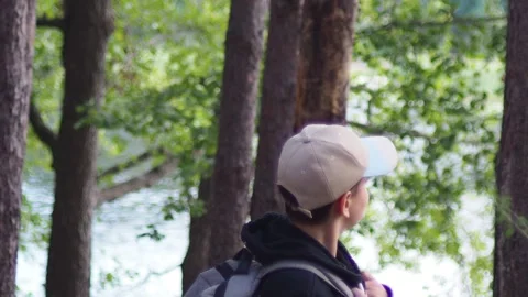 Active boy in a hat with a backpack stands in a summer pine forest Stock Footage 274879243