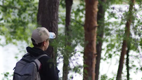 Active boy in a hat with a backpack stands in a summer pine forest Stock Footage 274879715