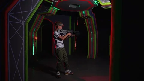 An active boy holding a laser weapon and aiming, a laser tag game. Stock Footage 321814249