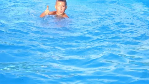 Active boy jumping into water and swimming Stock Footage 315030576