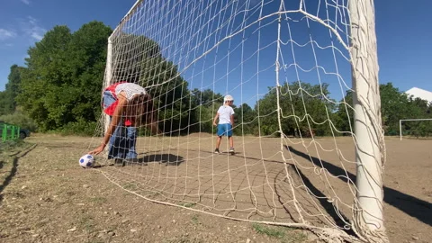 Active Boy Kicks Soccer Ball Near Goal While Mom Watches on Sunny Field Stock Footage 322121511