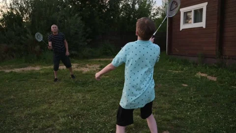 Active boy play badminton with cheerful grandfather outdoors in the courtyard of Stock Footage 208681454