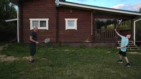 Active boy play badminton with cheerful grandfather outdoors in the courtyard of Stock Footage 208681527