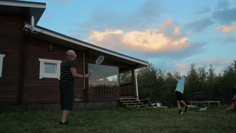 Active boy play badminton with cheerful grandfather outdoors in the courtyard of Stock Footage 208681661