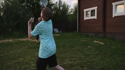 Active boy play badminton with cheerful grandfather outdoors in the courtyard of Stock Footage 254164864
