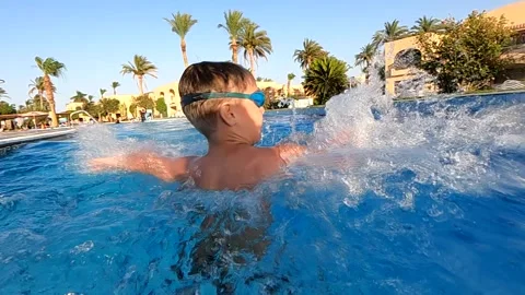 An active boy in a protective mask splashes in the pool, outdoor pool Stock Footage 246113344