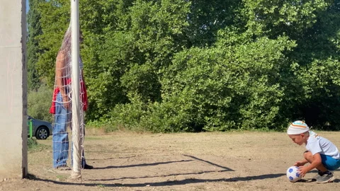 Active Boy Saves Soccer Ball While Mother Watches on Sunny Field Stock Footage 322121334