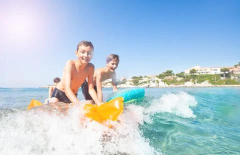 Active boys learning to ride the waves at seaside Stock-Fotos