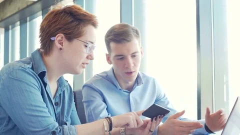 Active brainstorm of two young hardworking managers with laptop and mobile Stock Footage 73304432