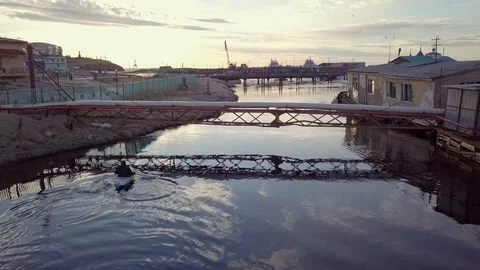 Active canoeist silhouette sails under metal gas pipe bridge Stock Footage 122493081