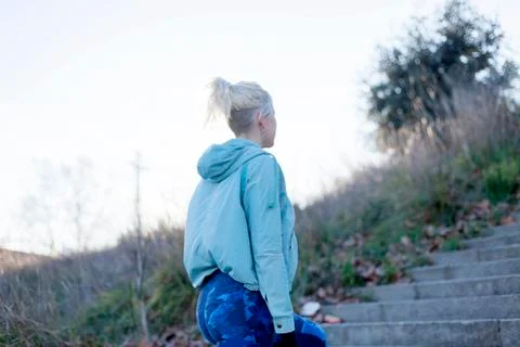 Active cheerful blonde pausing after a run in a park on a sunny day Stock Photos