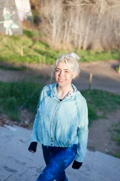 Active cheerful blonde pausing after a run in a park on a sunny day Stock Photos