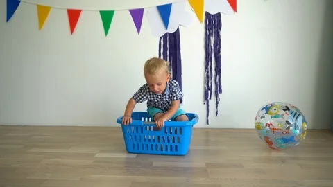 Active child boy fall off laundry box and play with ball. Gimbal motion Stock Footage 115406878