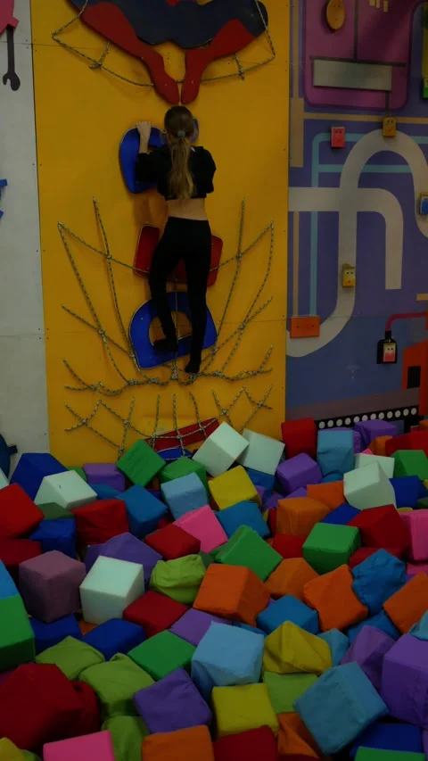 Active child is climbing up artificial wall. Brave little girl in entertainment Stock Footage 306128754