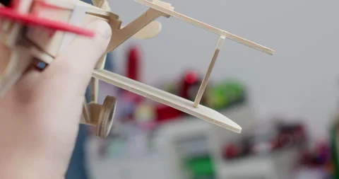 Active child hand moves small wooden airplane through space Stockbeeldmateriaal 323975088