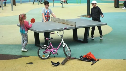 Active children from school play table tennis on the playground in the park. Stockbeeldmateriaal 239358585