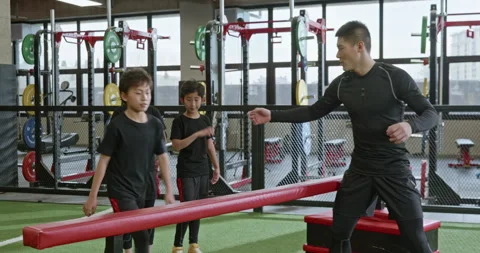Active Chinese children having exercise class with their coach in gym,4K Stock Footage 156724824