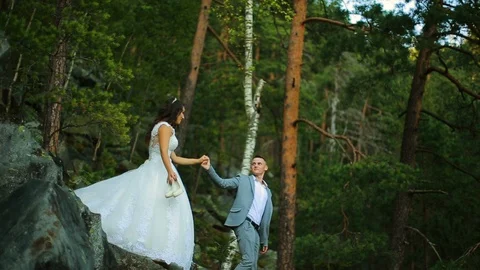 Active couple climbing on the rock in the forest with cliffs, pine trees Stock Footage 95840844