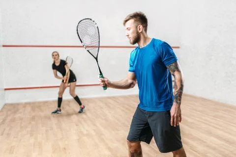 Active couple with rackets play squash game Stock Photos