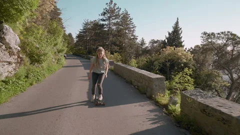 Active dreadlocks woman in sun rays longboarding on mountain background Stock Footage 131754443