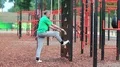 Active elderly athlete in green t-shirt trains in the open air gym HD Footage